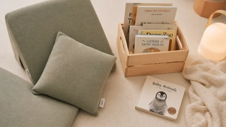 Coin lecture bebe cosy sur tapis crème, assise basse et livres